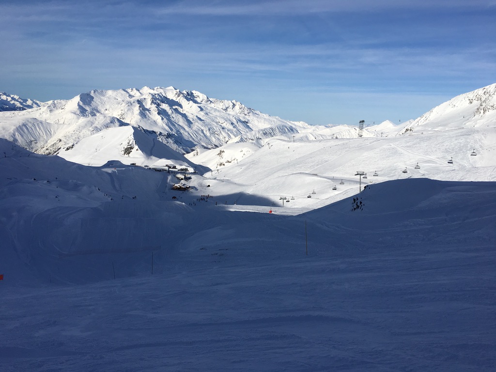 Alpine panorama, chairlifts crossing above the snowpark valley