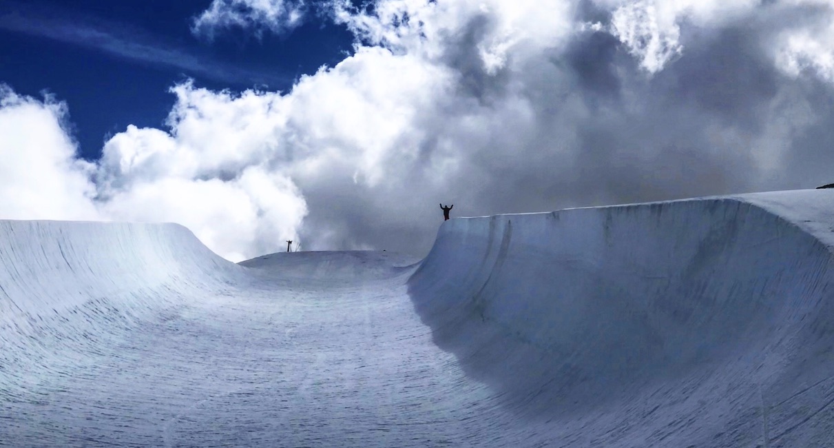 Superpipe walls in the clouds, a skier saluting from the deck